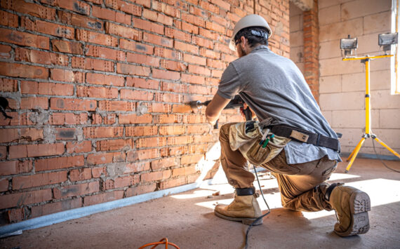 Mężczyzna na budowie przy ceglanej ścianie - Działalność transgraniczna - ryczałt a usługi budowlane w Niemczech